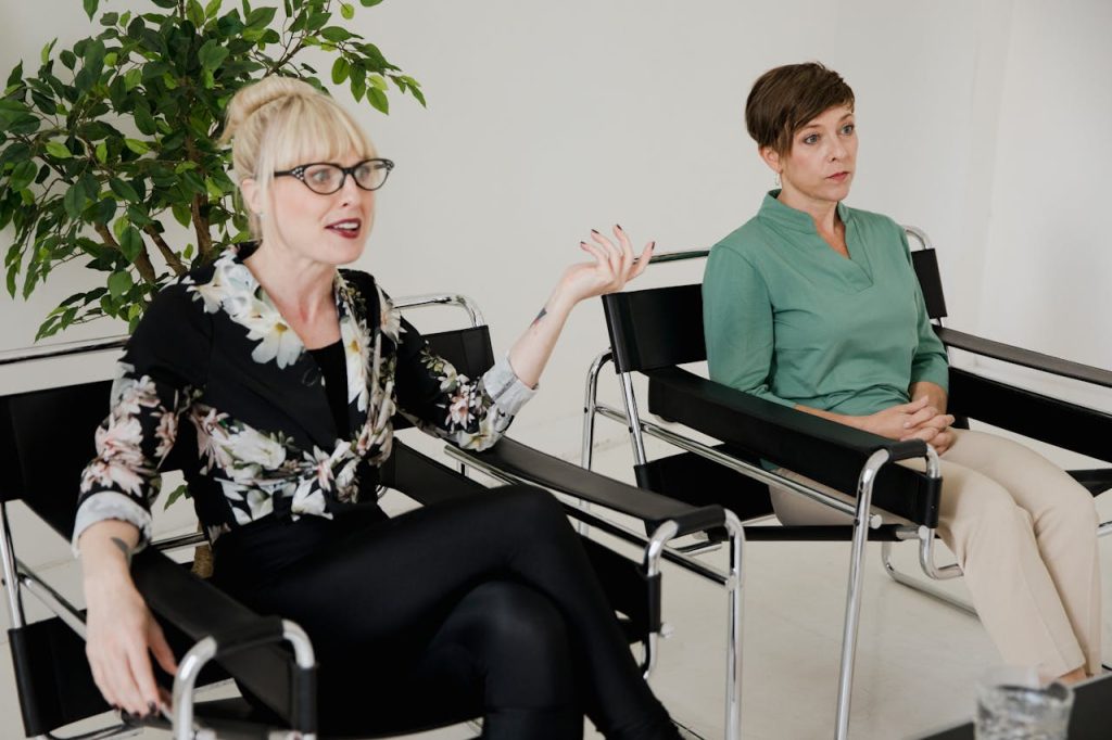 Two women having a conversation in a modern therapy office setting.